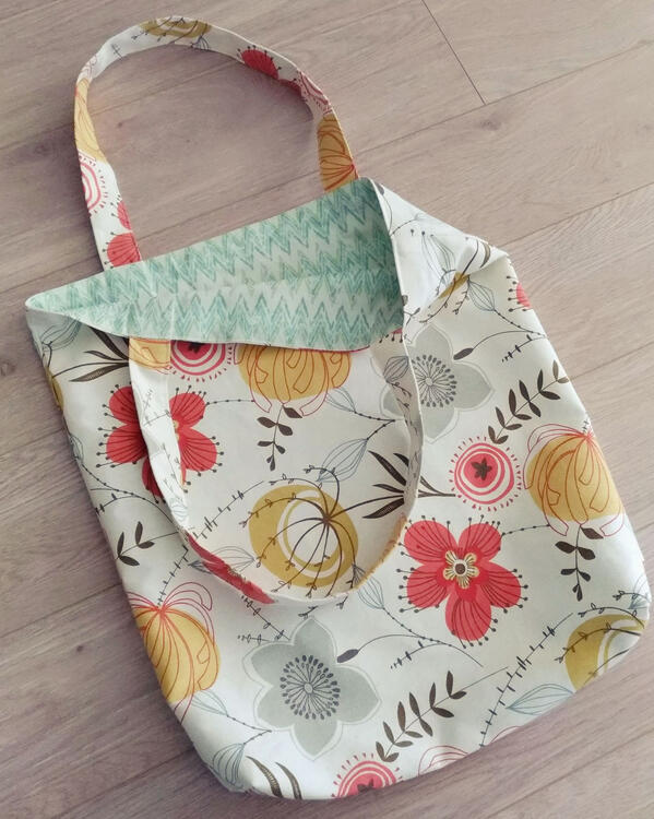 tote bag with pink, yellow, and white flower pattern, and a teal inner lining