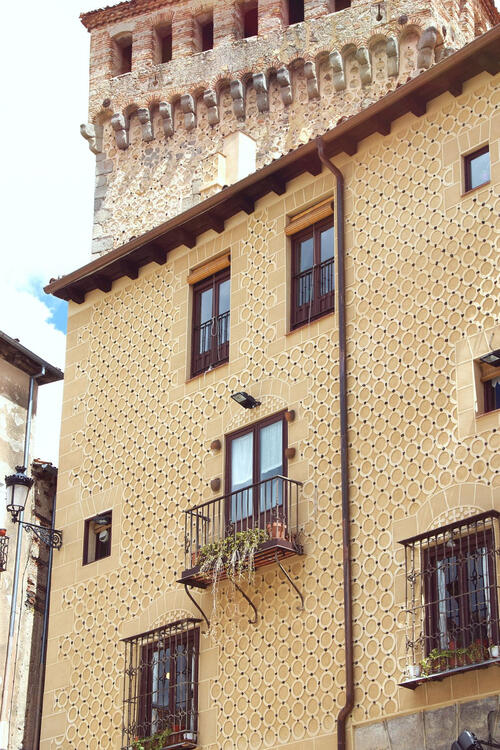 beige coloured facade of an historical building with decorative patterns and a door with a balcony