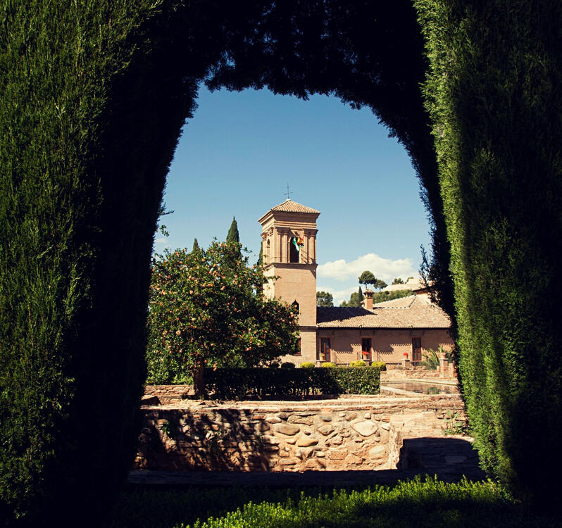 view of a historical building through a topiary archway